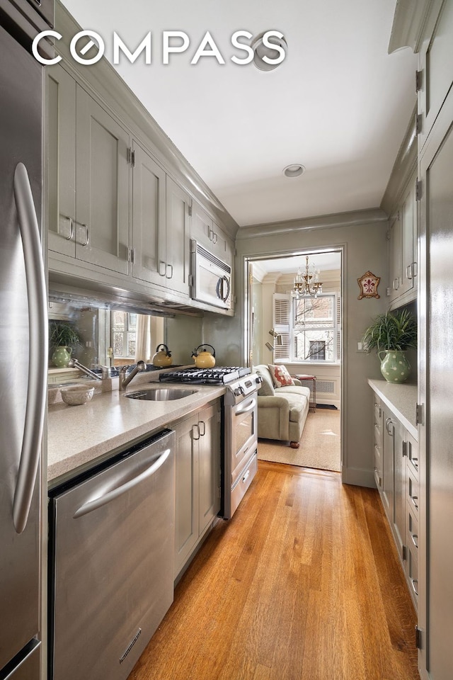 kitchen featuring appliances with stainless steel finishes, light wood-type flooring, gray cabinets, and a sink