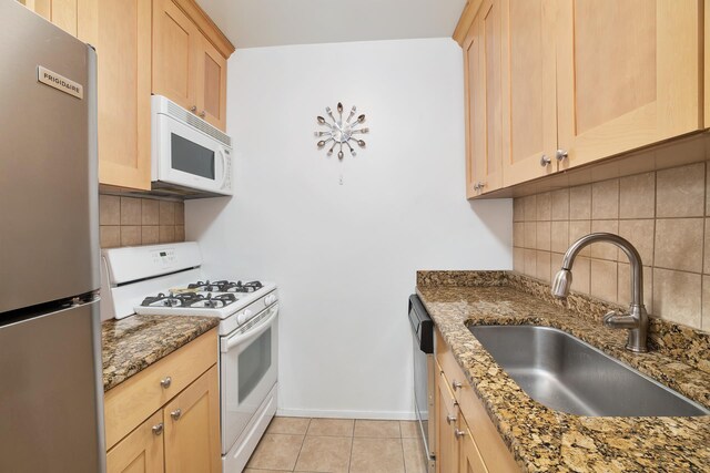 kitchen with light brown cabinetry, appliances with stainless steel finishes, and a sink