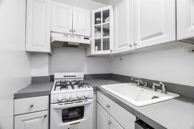 kitchen with white gas range, under cabinet range hood, a sink, white cabinetry, and glass insert cabinets