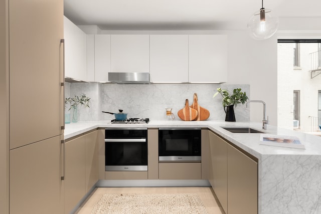 kitchen featuring white appliances, modern cabinets, decorative light fixtures, under cabinet range hood, and a sink