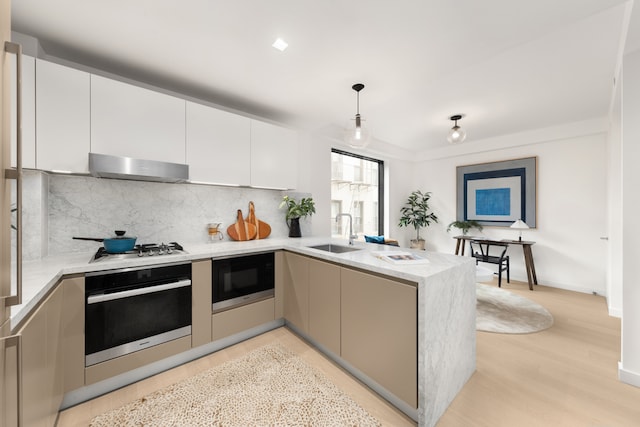 kitchen with wall oven, a peninsula, under cabinet range hood, black microwave, and a sink