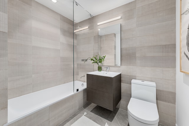 bathroom featuring tiled shower / bath combo, toilet, tile walls, and vanity