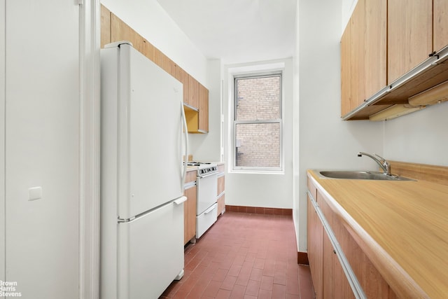 kitchen with white appliances, a sink, brick floor, and light countertops