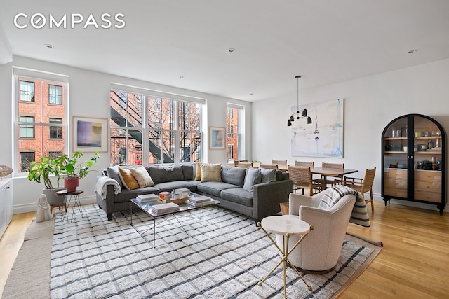 living area featuring light wood-style flooring, baseboards, and recessed lighting