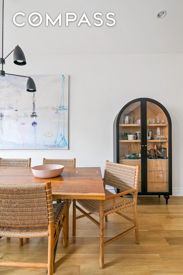 dining room with light wood-type flooring, arched walkways, and recessed lighting