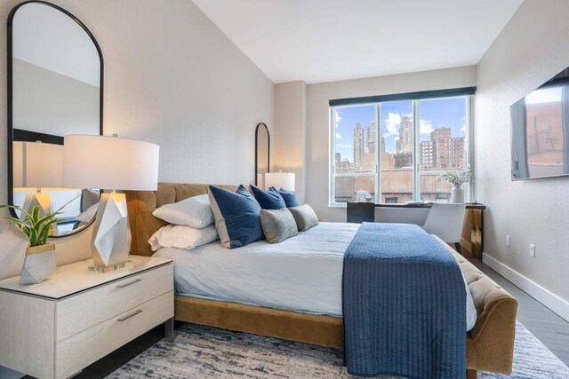 bedroom featuring baseboards, vaulted ceiling, and wood finished floors