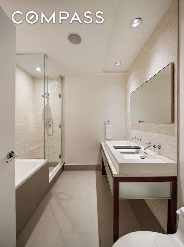 bathroom featuring a sink, baseboards, a bath, double vanity, and a stall shower