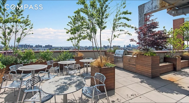 view of patio / terrace featuring a view of city, outdoor dining area, and area for grilling