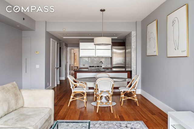 dining area featuring dark wood-type flooring and baseboards