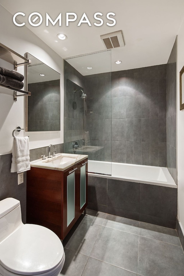 bathroom with visible vents, toilet, tiled shower / bath combo, vanity, and tile patterned floors