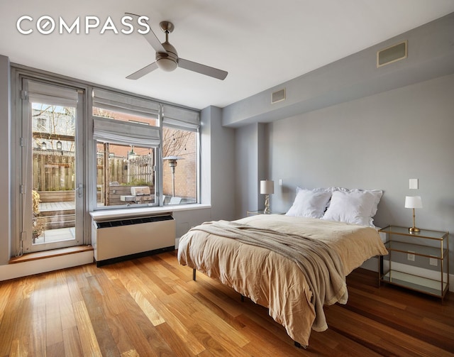 bedroom with light wood-type flooring, radiator heating unit, visible vents, and a ceiling fan