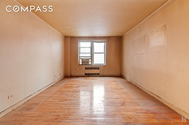 spare room featuring radiator and light wood finished floors