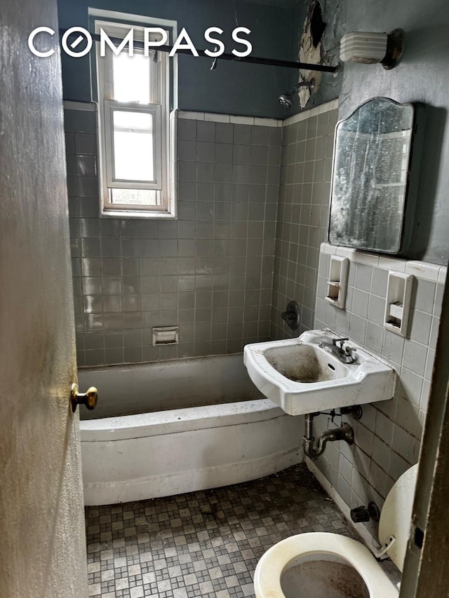 full bathroom with toilet, washtub / shower combination, tile walls, and a sink