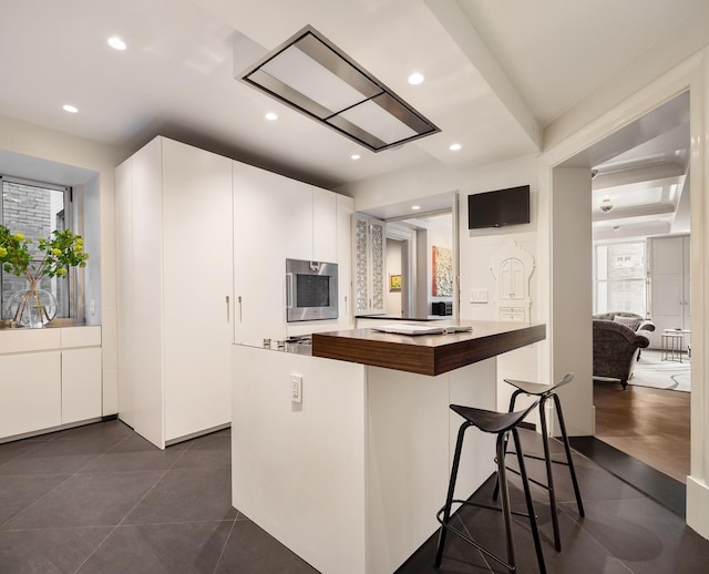 kitchen with oven, recessed lighting, butcher block countertops, a kitchen island, and white cabinetry