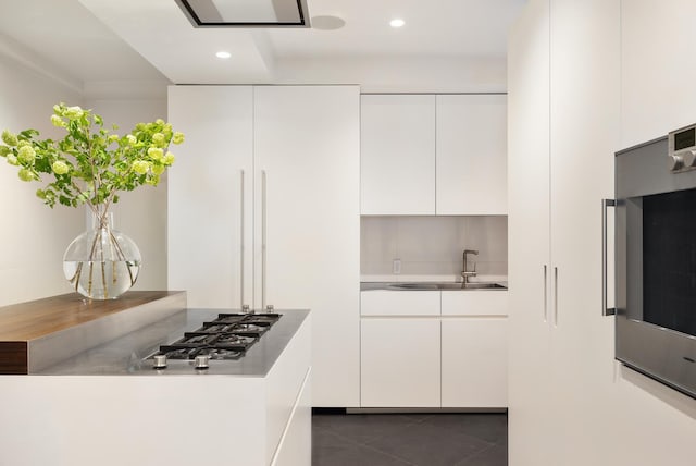 kitchen featuring recessed lighting, dark tile patterned flooring, a sink, white cabinets, and modern cabinets