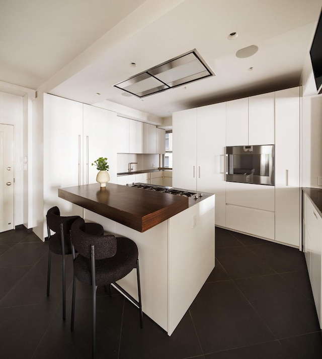 kitchen with dark tile patterned floors, stainless steel oven, modern cabinets, and white cabinetry