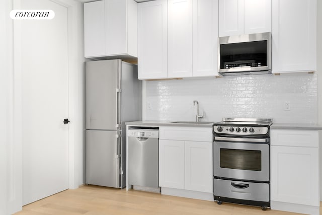 kitchen featuring stainless steel appliances, white cabinets, light countertops, and a sink