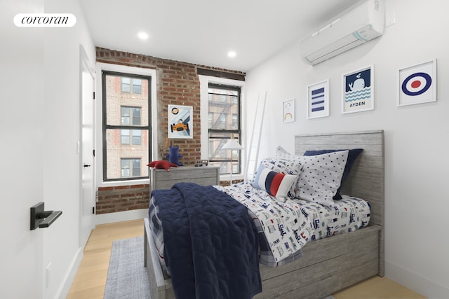 bedroom featuring light wood finished floors, visible vents, an AC wall unit, brick wall, and baseboards