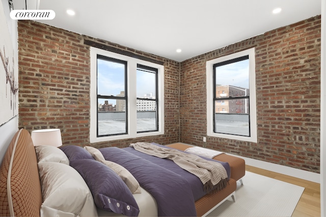 bedroom with brick wall, baseboards, light wood-style flooring, and recessed lighting