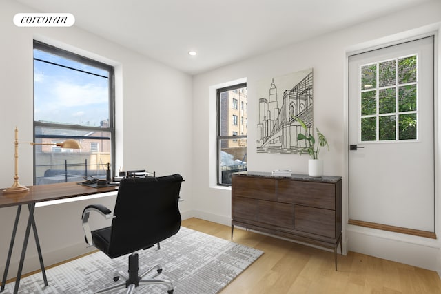 office with baseboards, light wood-style flooring, visible vents, and a healthy amount of sunlight