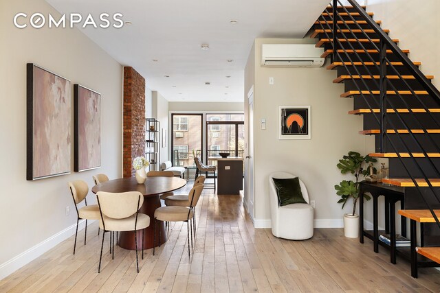 dining area featuring a wall mounted AC, wood-type flooring, and baseboards