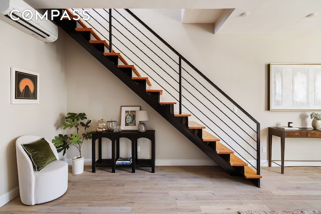 stairway featuring wood finished floors, baseboards, and a wall mounted air conditioner