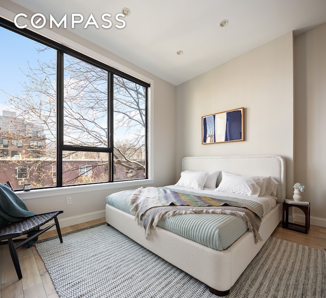 bedroom featuring multiple windows, wood finished floors, baseboards, and recessed lighting