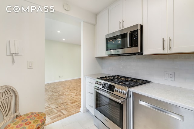 kitchen with stainless steel appliances, tasteful backsplash, and white cabinets