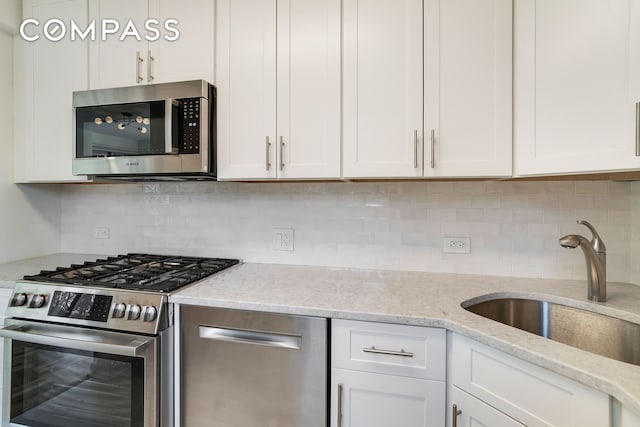 kitchen featuring a sink, stainless steel appliances, tasteful backsplash, and white cabinets