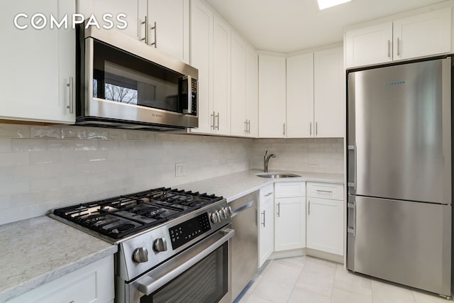 kitchen with backsplash, white cabinets, stainless steel appliances, and a sink