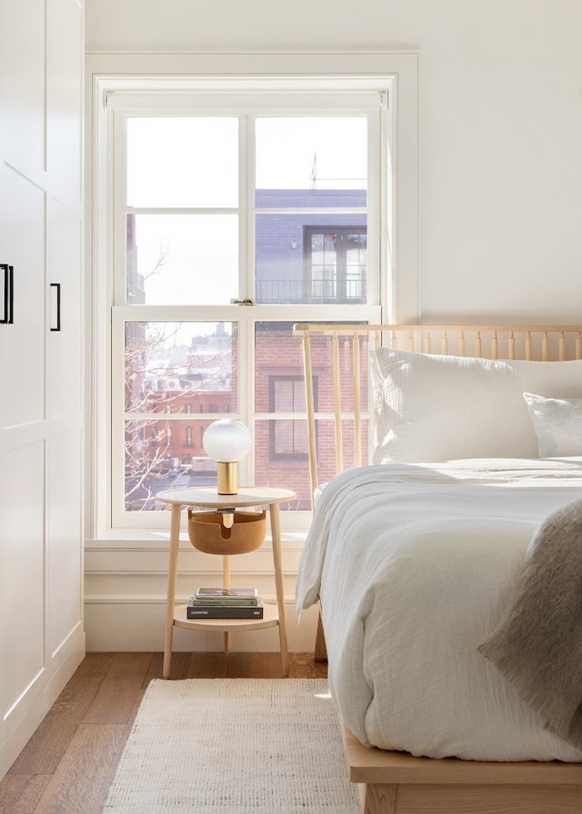 bedroom with multiple windows, a decorative wall, and wood finished floors