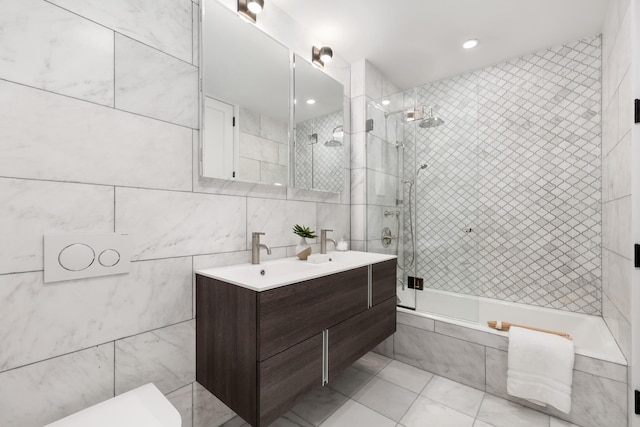 full bathroom featuring tiled shower / bath, a sink, tile walls, and double vanity