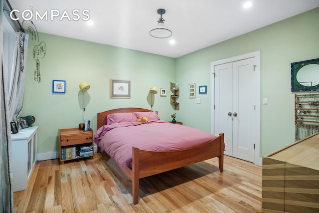 bedroom with a closet, light wood-type flooring, and baseboards