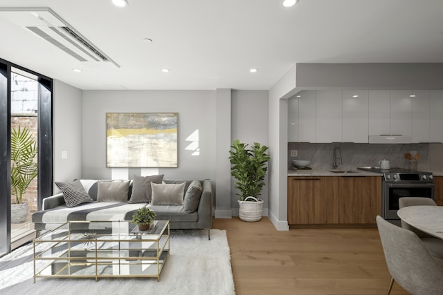 living area featuring light wood-style flooring, expansive windows, baseboards, and recessed lighting