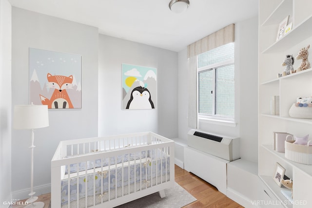 bedroom with a crib and light wood-type flooring