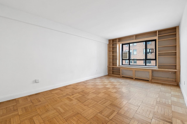 empty room featuring radiator, built in shelves, and baseboards