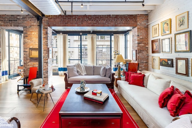 living room with hardwood / wood-style flooring, beamed ceiling, and brick wall