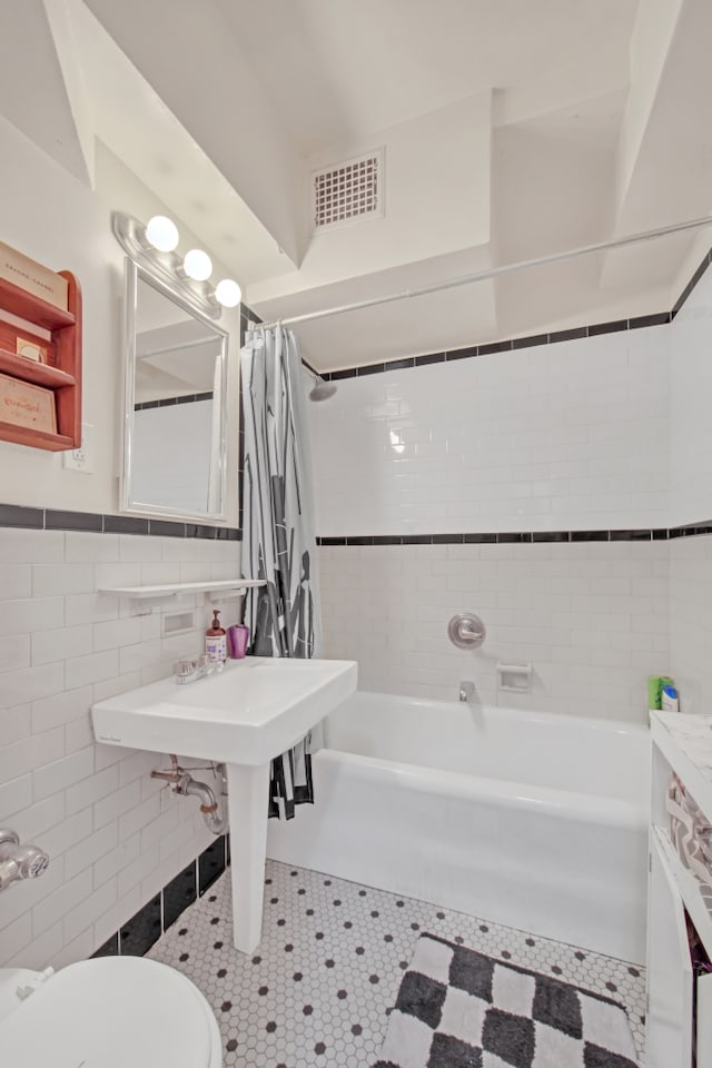 227 E 57th St Unit 9Fg, New York City, NY 10022 - bathroom featuring toilet, shower / tub combo, visible vents, tile walls, and wainscoting