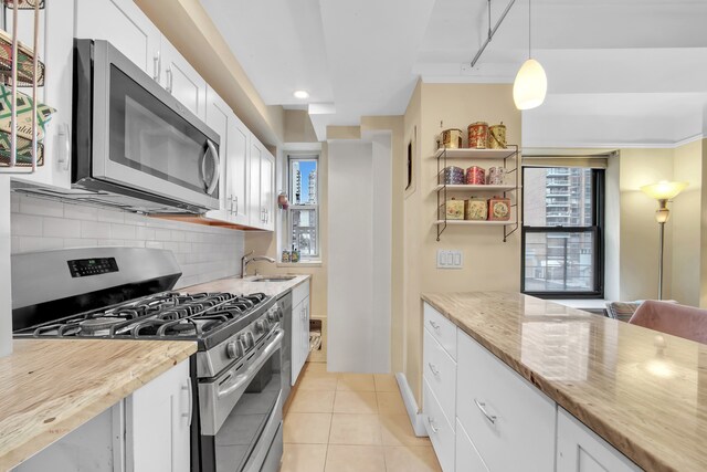 227 E 57th St Unit 9Fg, New York City, NY 10022 - kitchen featuring appliances with stainless steel finishes, backsplash, white cabinetry, plenty of natural light, and recessed lighting