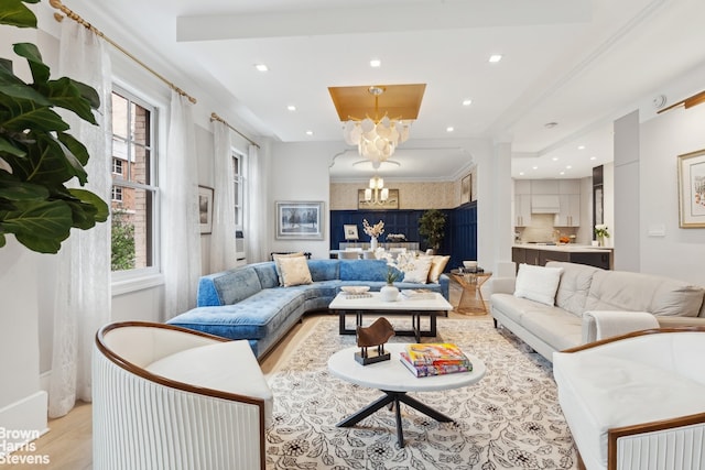 living room with ornamental molding, recessed lighting, light wood finished floors, and an inviting chandelier