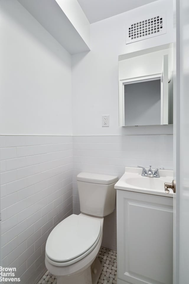 330 E 79th St Unit 1A, New York City, NY 10075 - half bathroom with vanity, tile walls, wainscoting, and tile patterned floors