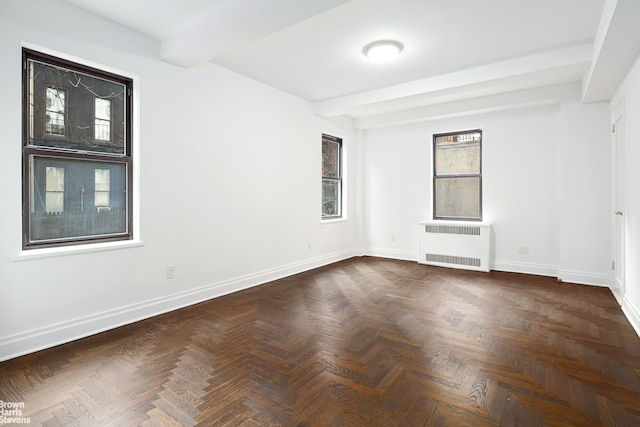 empty room with beam ceiling, radiator, and baseboards