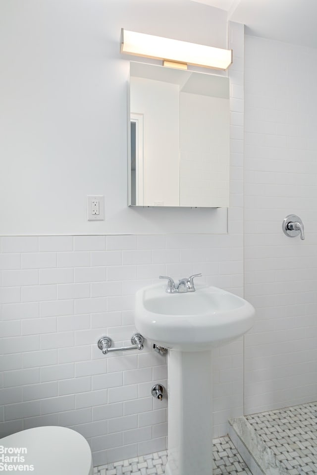 full bath with toilet, tiled shower, and tile walls