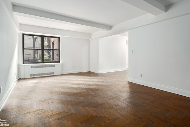 empty room with radiator heating unit, baseboards, and beamed ceiling