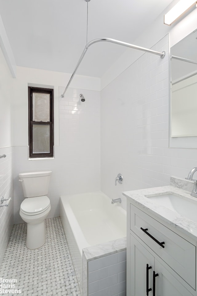 bathroom featuring toilet, tub / shower combination, vanity, and tile walls