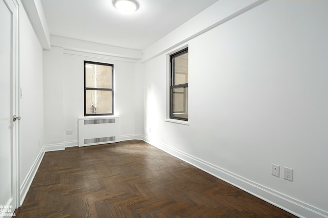 empty room with radiator heating unit and baseboards