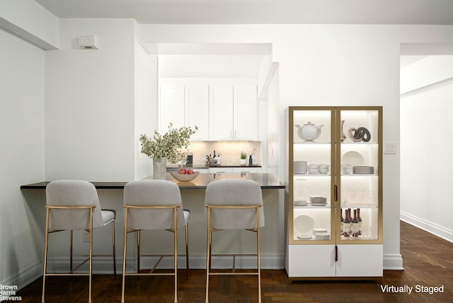 330 E 79th St Unit 1A, New York City, NY 10075 - kitchen featuring white cabinets, a breakfast bar, decorative backsplash, dark countertops, and a peninsula