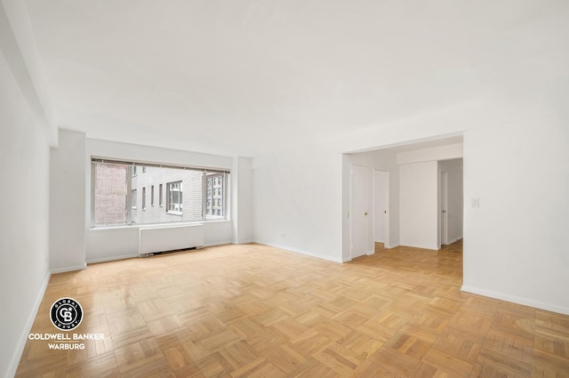 empty room with radiator heating unit and baseboards