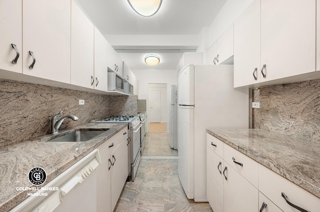 200 E 57th St Unit 9G, New York City, NY 10022 - kitchen with white cabinetry, tasteful backsplash, a sink, light stone countertops, and white appliances