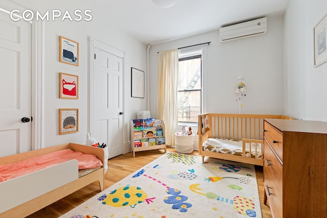 bedroom featuring light wood-style floors and a wall mounted air conditioner